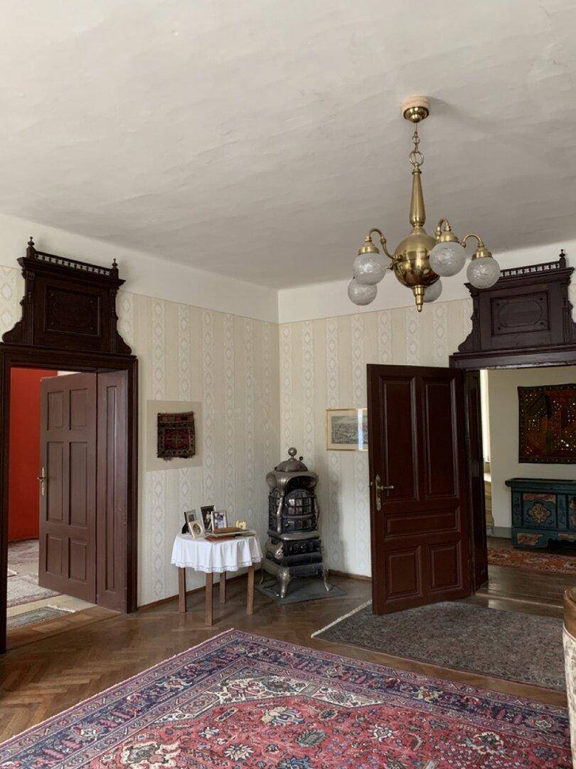 Historischer Flur mit Holztüren, Parkettboden und einem antiken Ofen.