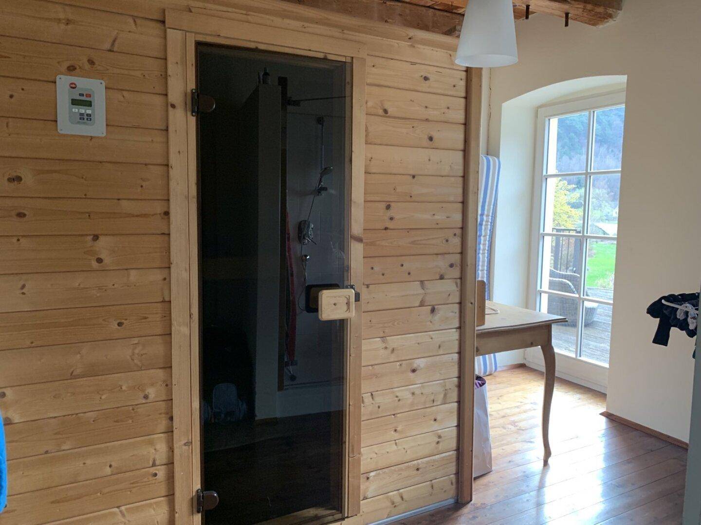 Wellnessbereich mit einer holzvertäfelten Sauna und Blick ins Grüne.