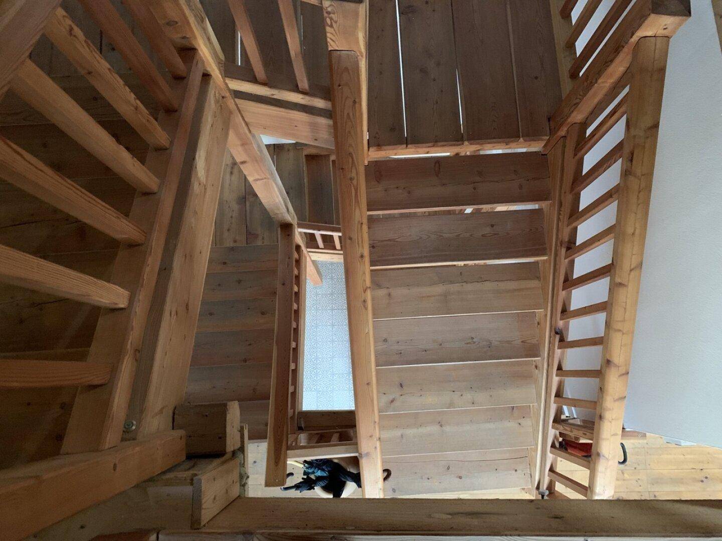 Rustikale Holztreppe in einem Gebäude mit sichtbaren Holzbalken.