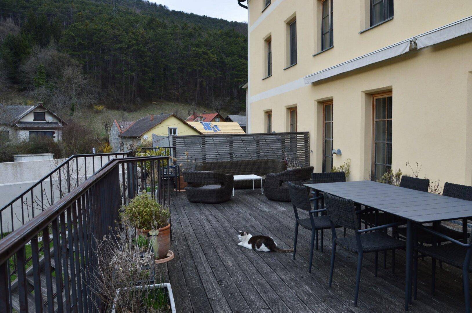 Große Holzterrasse mit Sitzgelegenheiten und Blick auf die umliegende Landschaft.