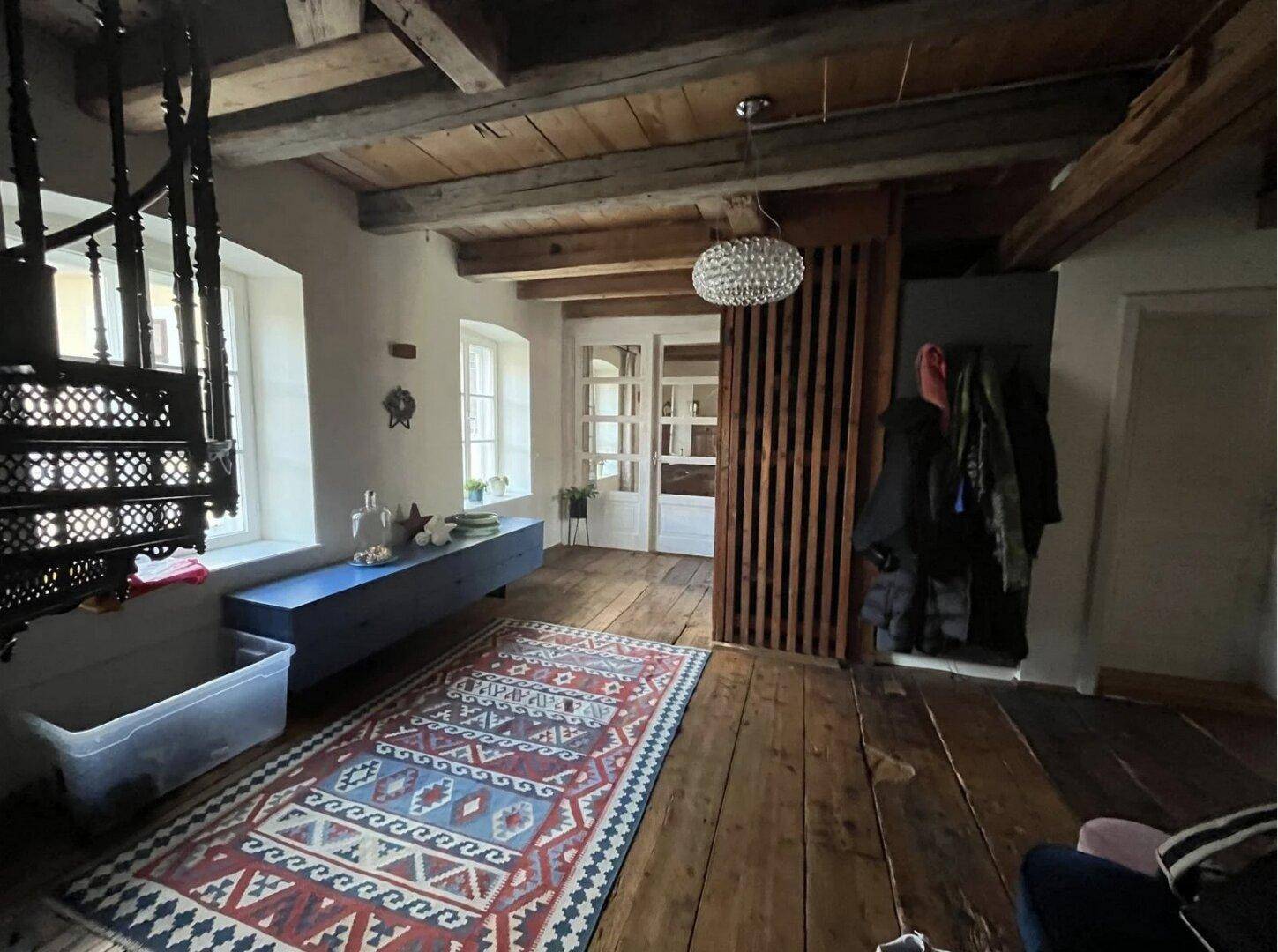 Flur mit Holzbalkendecke, breiten Dielen und einer dekorativen Wendeltreppe.