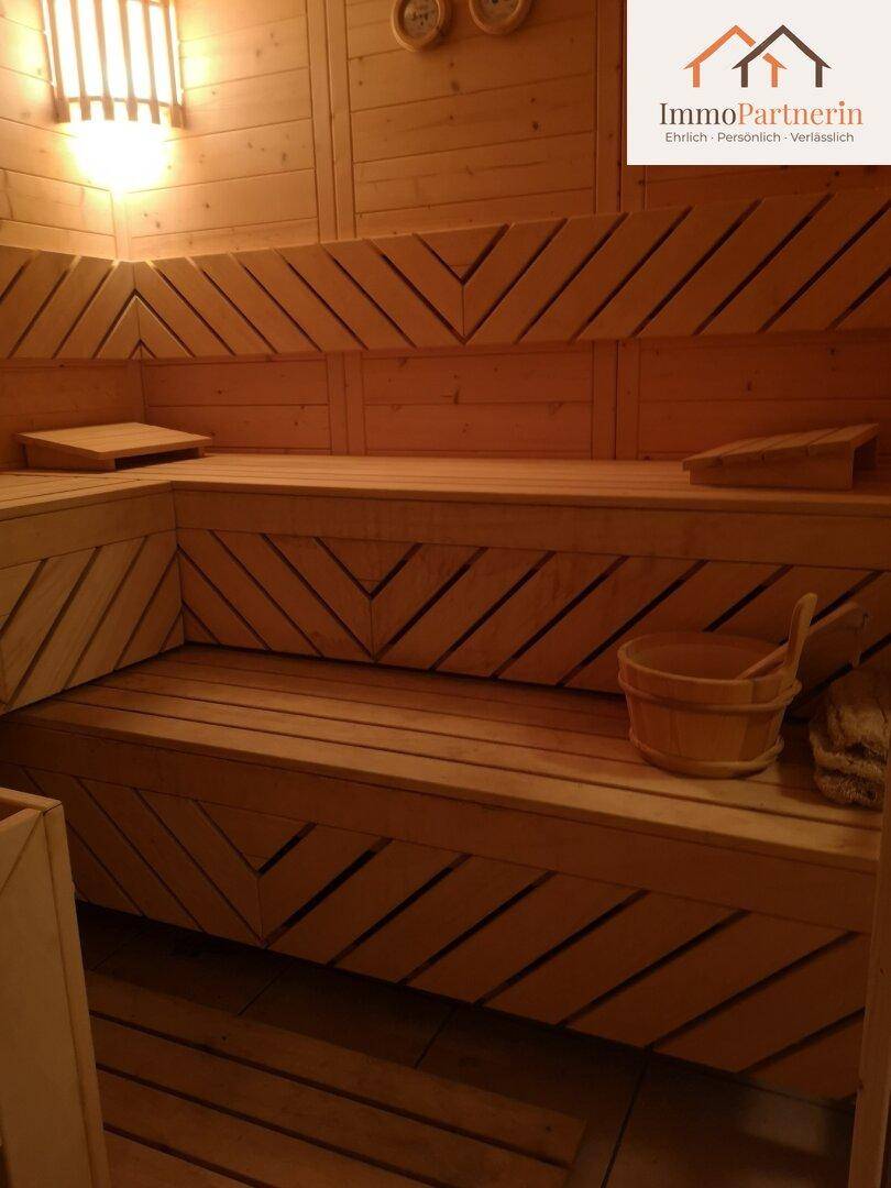 Traditionelle Holzsauna mit Sitzbänken und Saunaeimer für entspannende Momente.