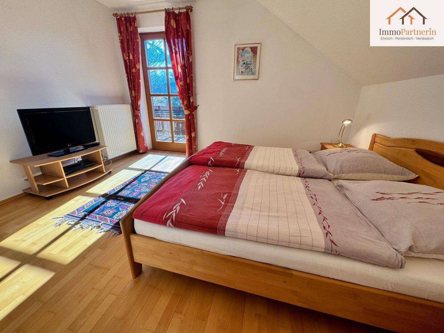 Freundliches Schlafzimmer mit zwei Einzelbetten, Holzboden und Zugang zu einem Außenbereich.
