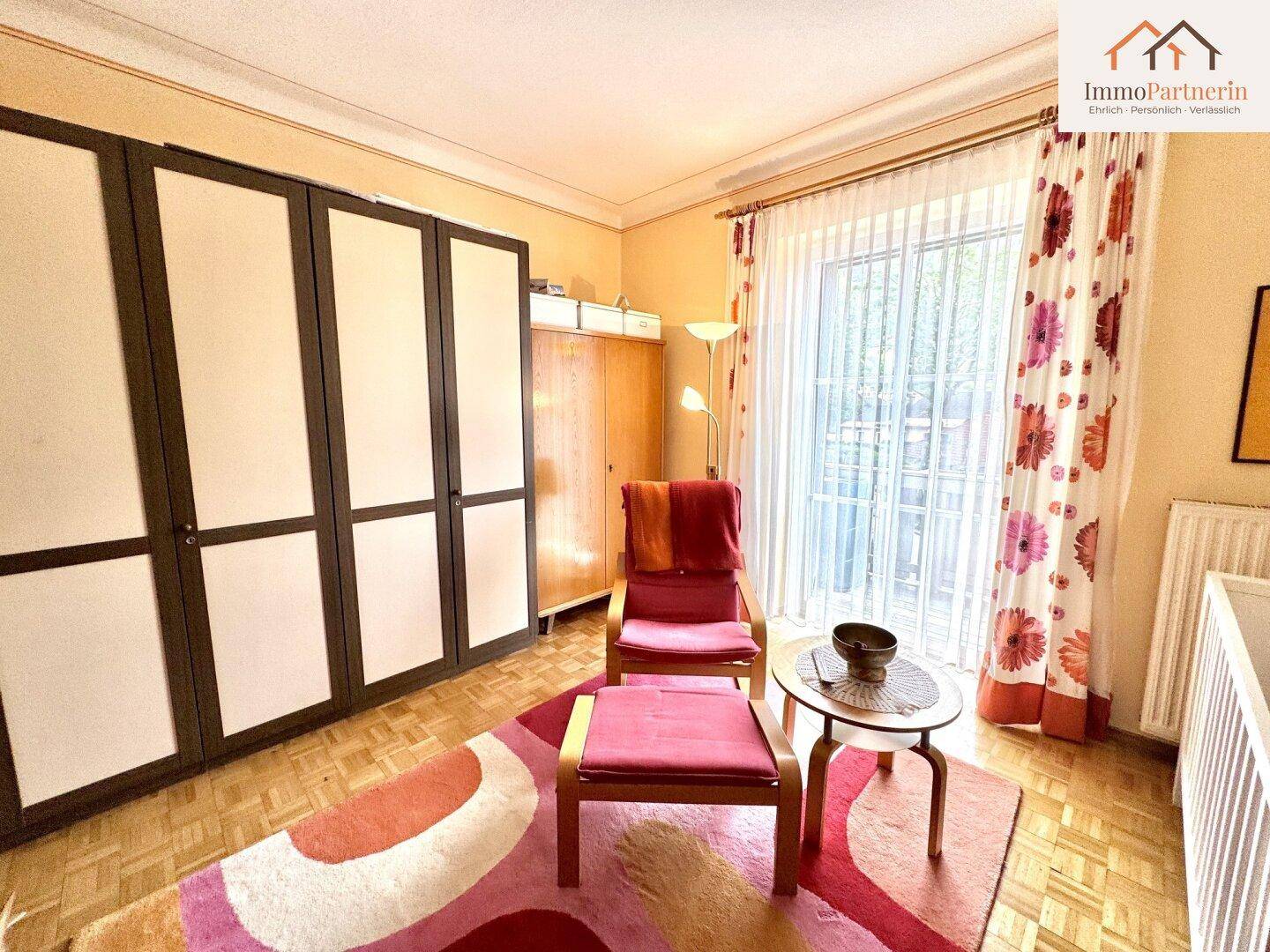 Helles Schlafzimmer mit großem Kleiderschrank, Teppich und Zugang zu einem Balkon.