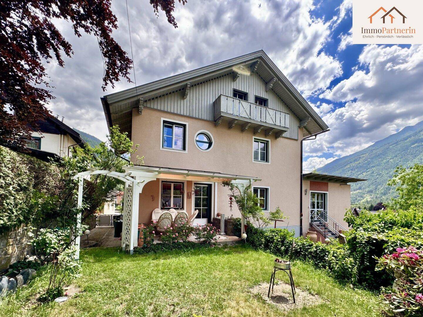 Ansicht des Hauses von der Gartenseite mit überdachter Terrasse und gepflegtem Rasen.