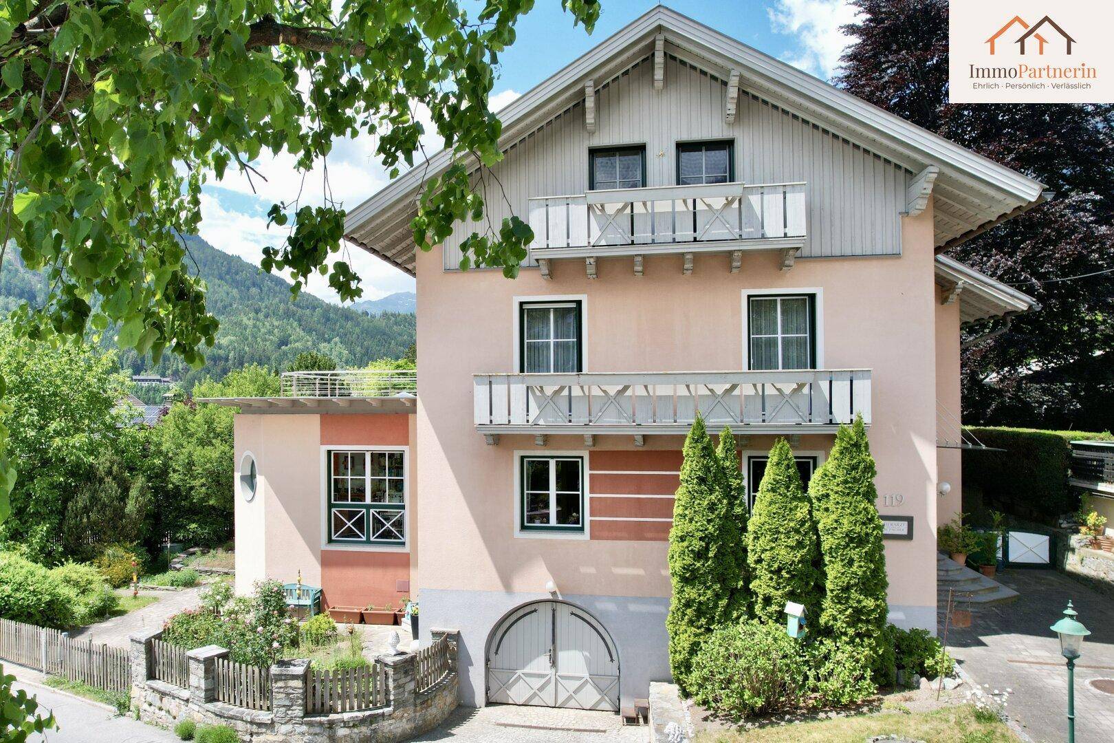 Charmantes Haus mit mehreren Balkonen und Blick auf die umliegende Berglandschaft.