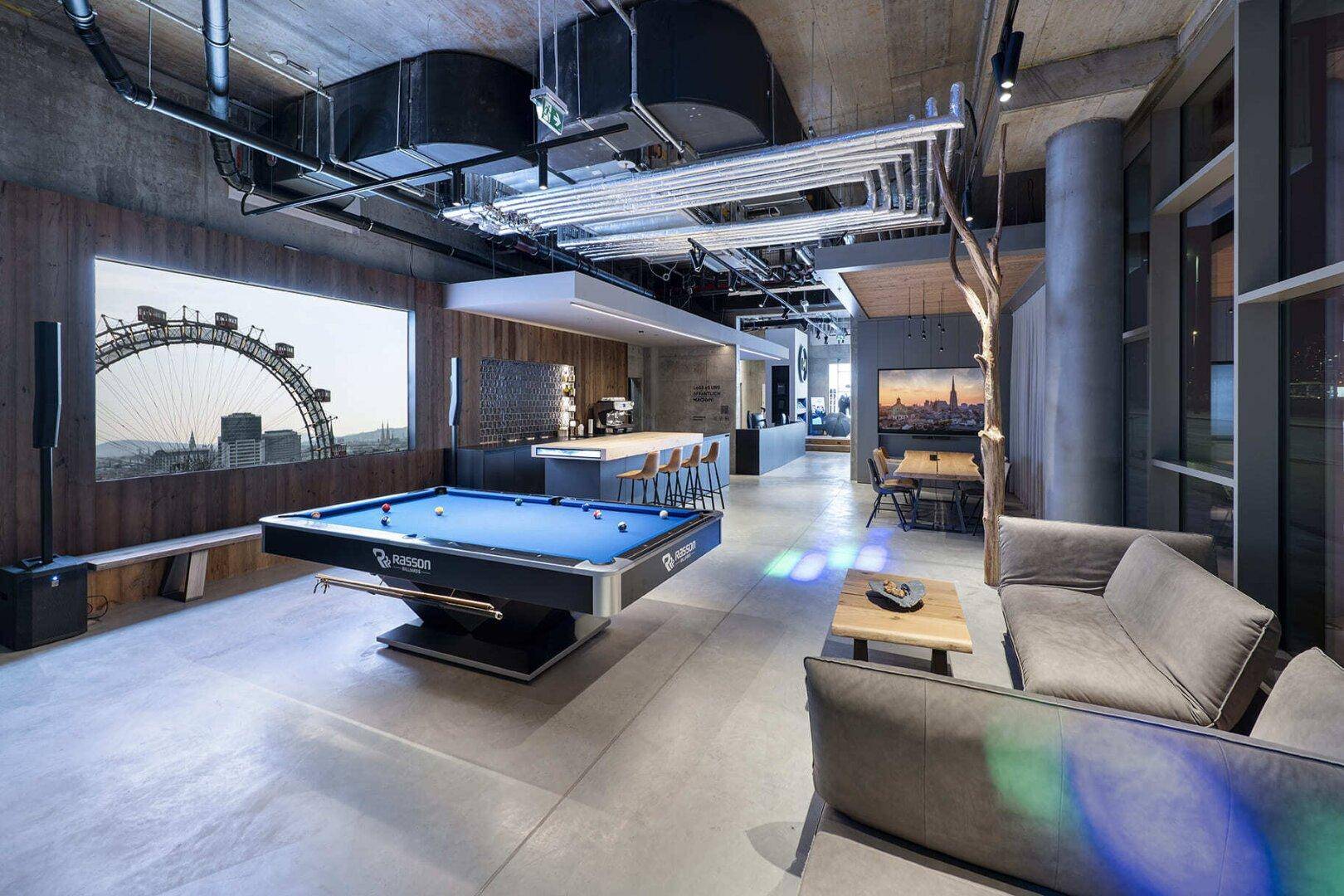 Offener Loungebereich mit Billardtisch, bequemen Sofas und Blick auf eine Stadtlandschaft.