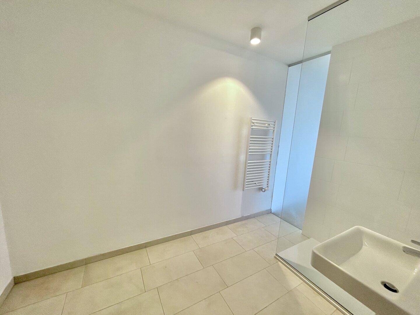 Modernes Badezimmer mit begehbarer Dusche, Einzelwaschbecken und Handtuchheizkörper.