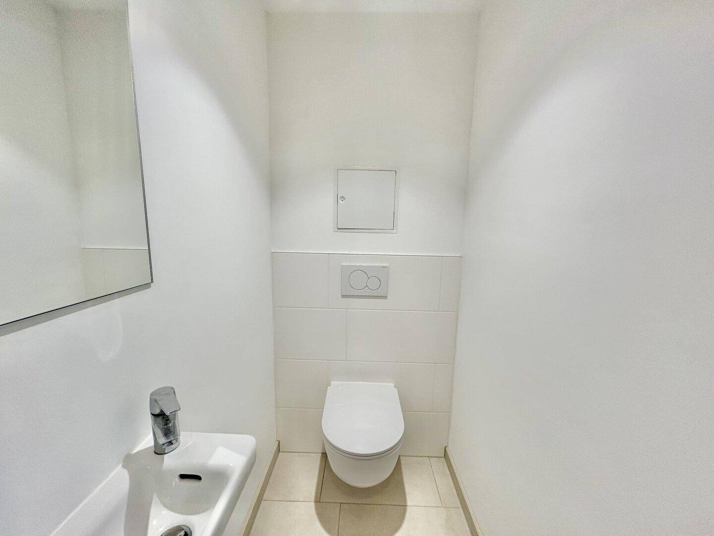 Separates Gäste-WC mit wandhängender Toilette und kleinem Handwaschbecken.
