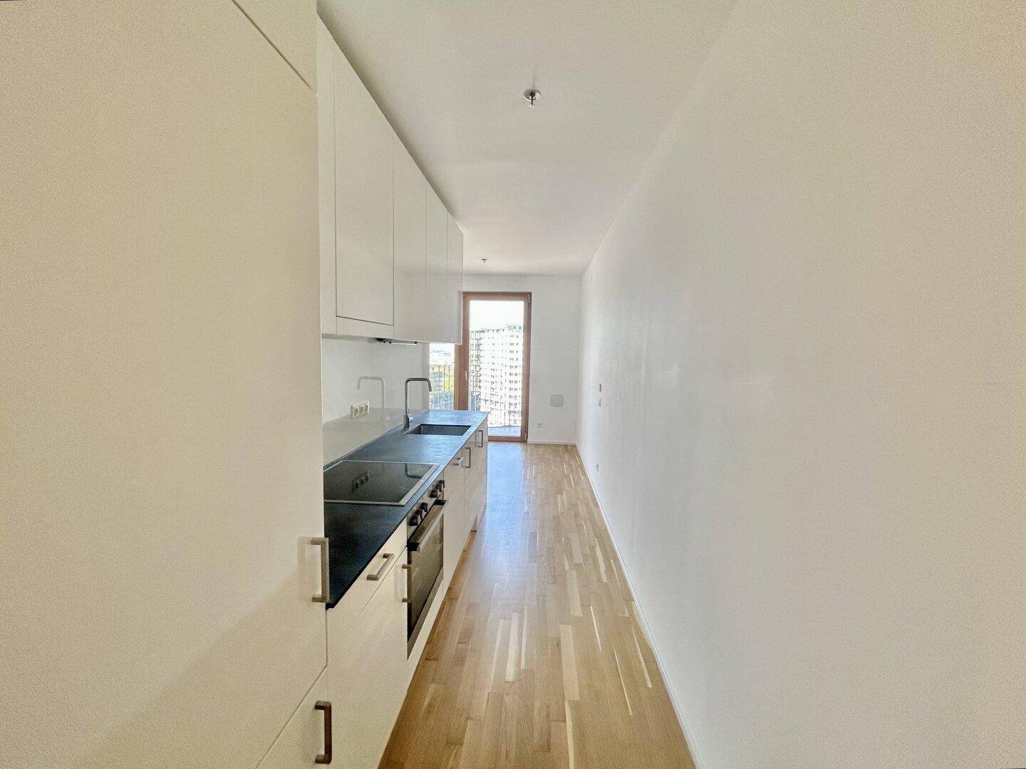 Schmale Küchenzeile in einem offenen Raum mit Zugang zu einem Balkon.