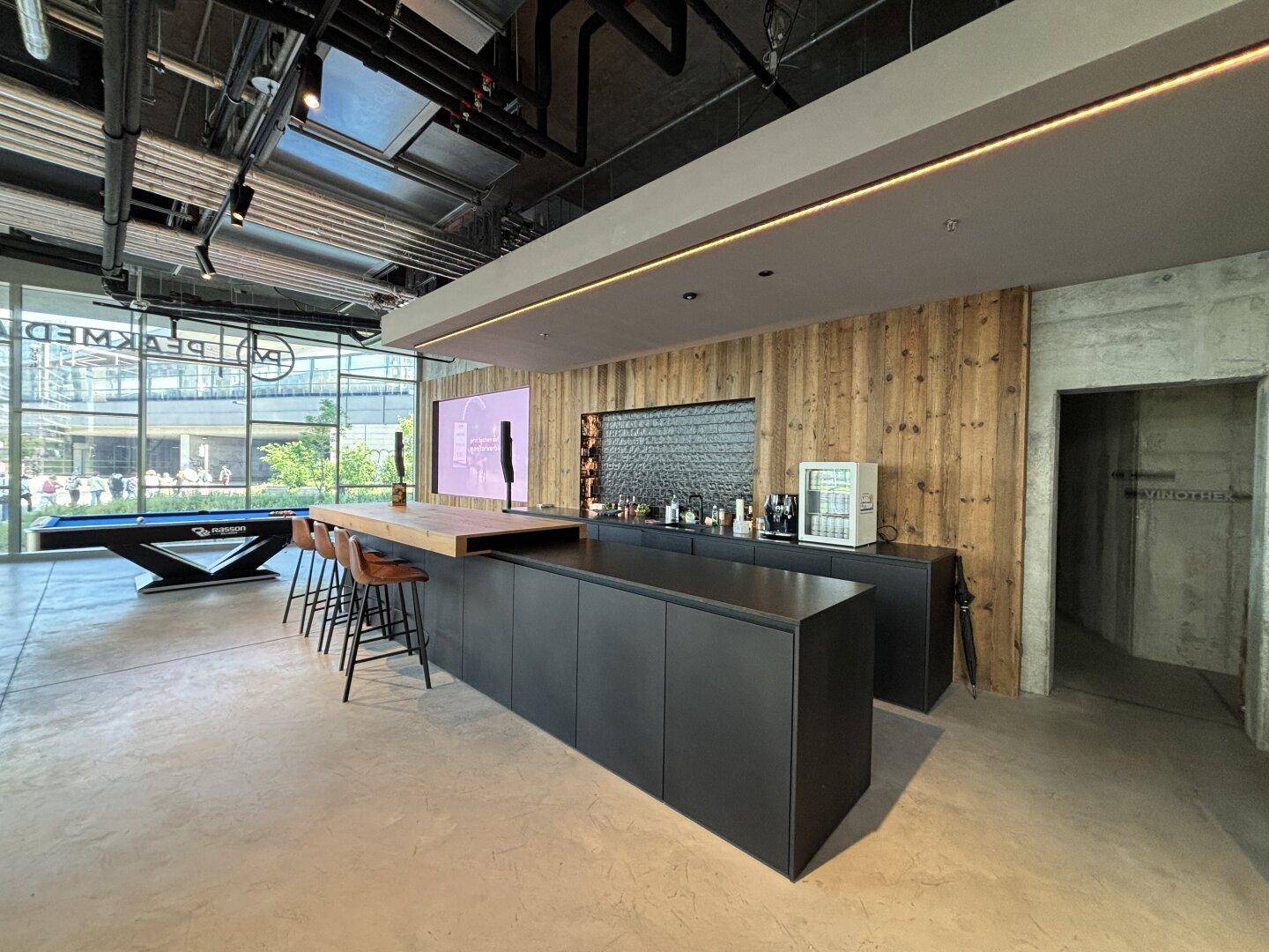 Stilvolle Bar mit Holzakzenten, dunklen Schränken und einer langen Theke, ideal für Getränke und Snacks.