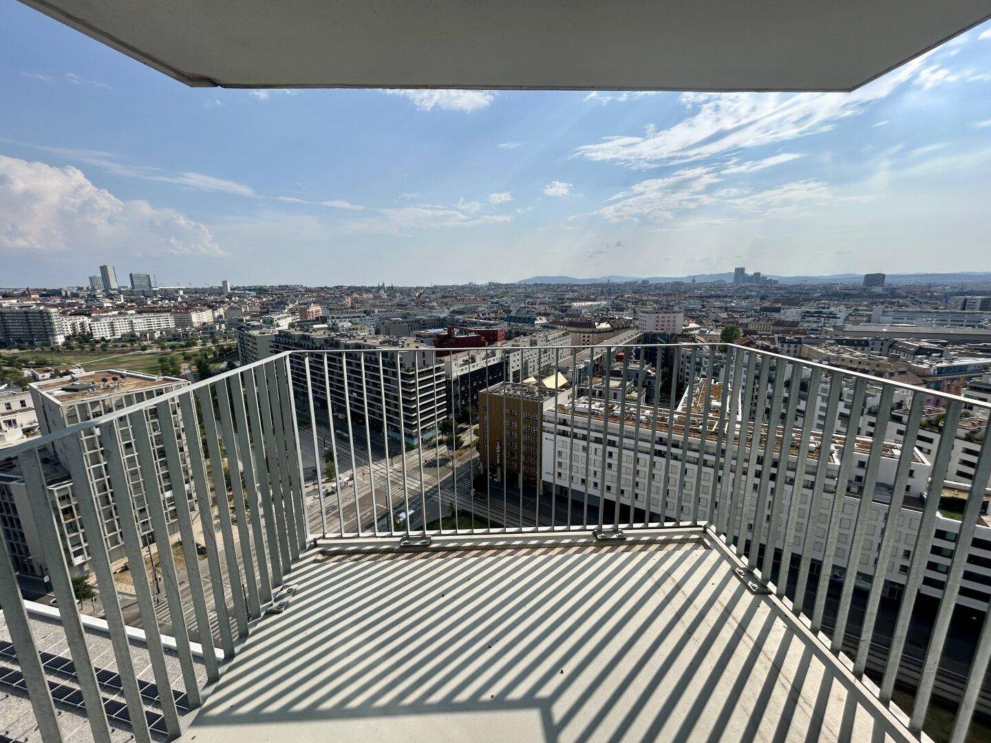 Geräumiger Balkon mit Metallgeländer und weitem Panoramablick über die Stadt.