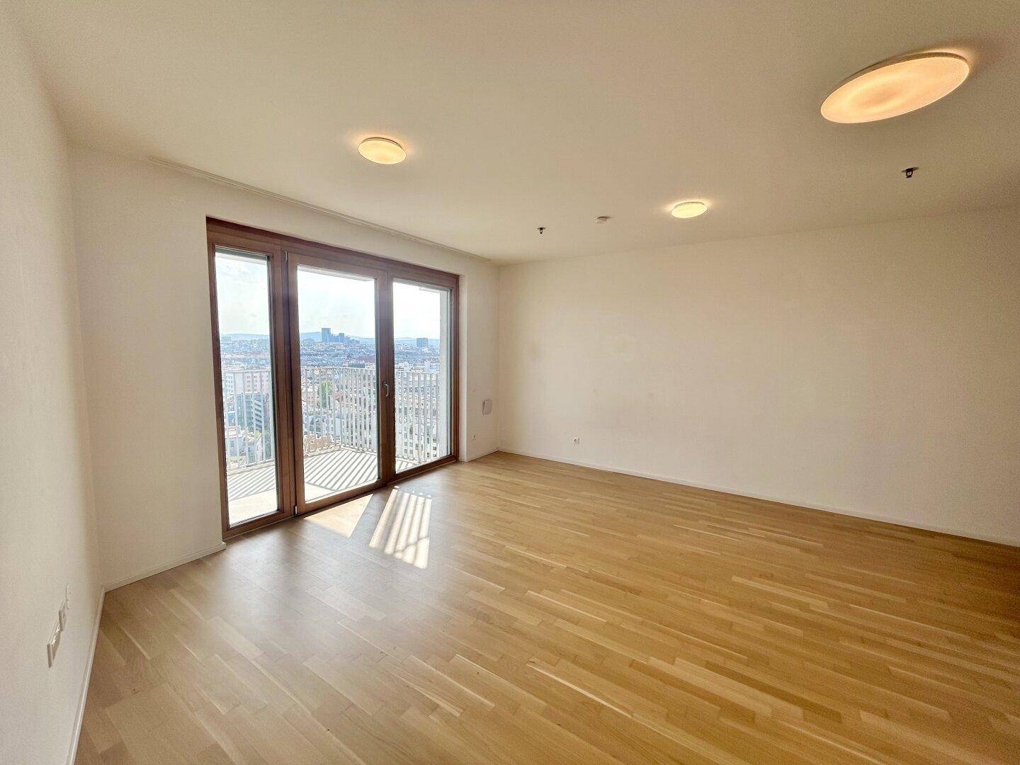 Heller Wohnraum mit Holzboden und großen Fenstern, die einen beeindruckenden Stadtblick ermöglichen.