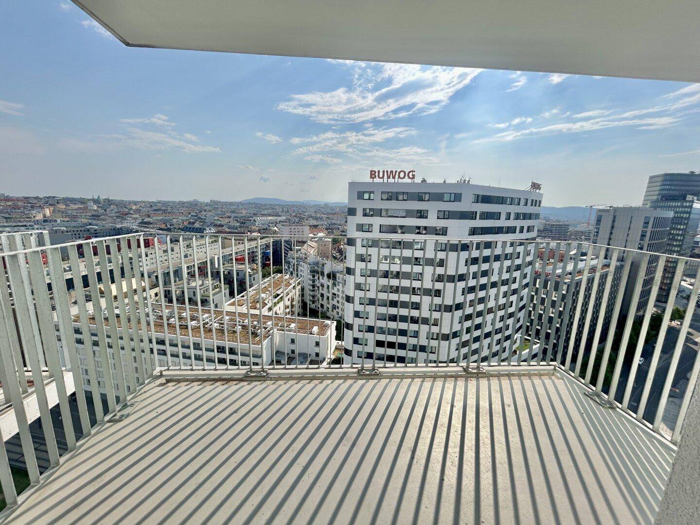 Geräumiger Balkon mit Metallgeländer und weitem Blick über die Stadtlandschaft.