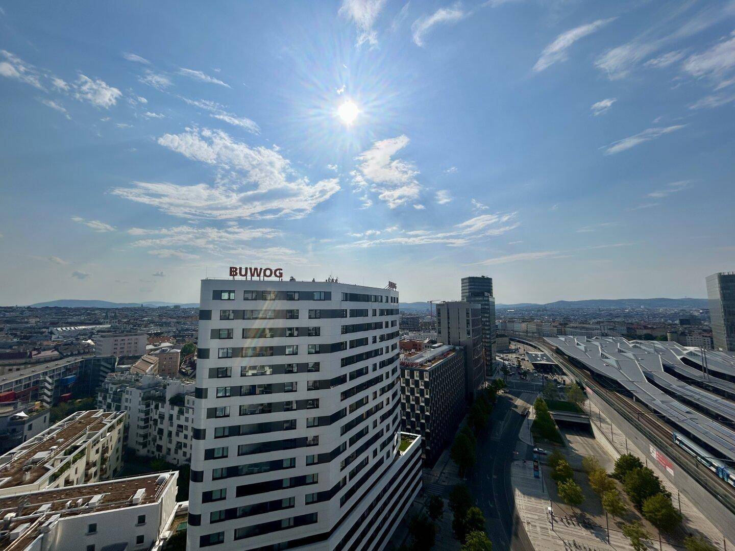 Weitläufiger Stadtblick von oben mit Sonnenschein und urbaner Architektur.