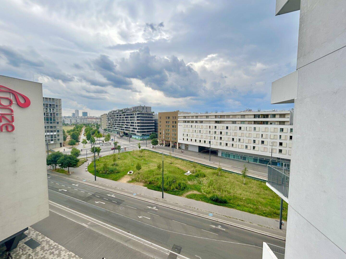 Weitläufiger Blick vom Balkon über die Stadtlandschaft mit Grünflächen und modernen Gebäuden.