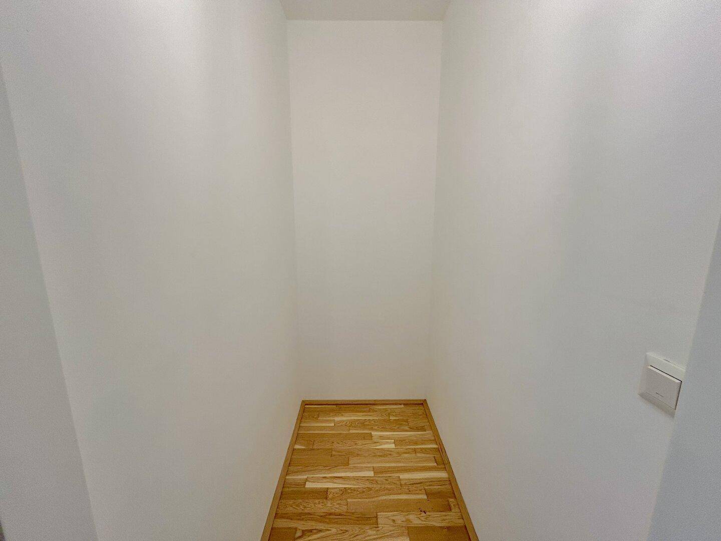 Praktischer Abstellraum mit Parkettboden und weißen Wänden, ideal für zusätzlichen Stauraum.