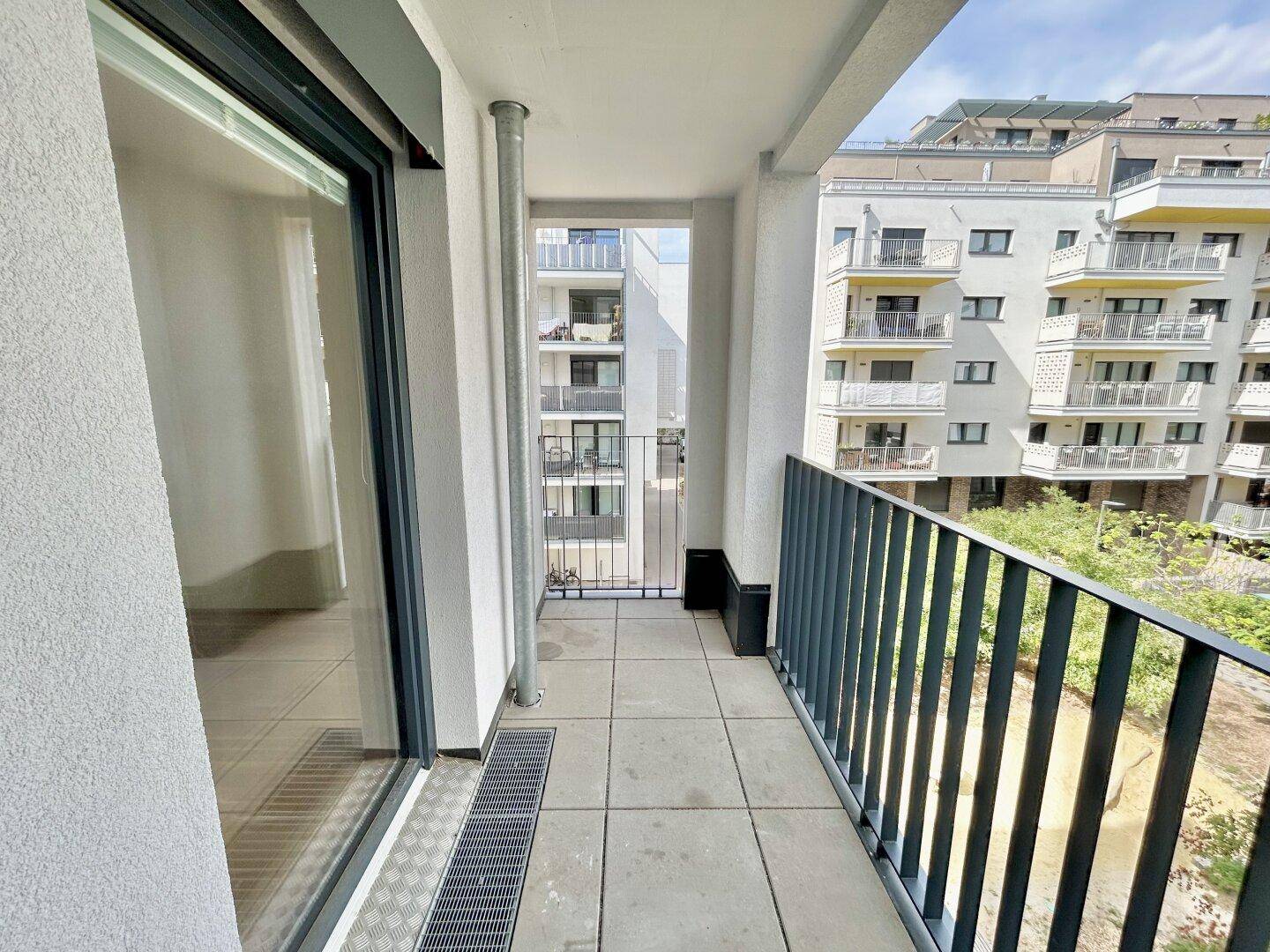Geräumiger Balkon mit Fliesenboden und Blick auf die umliegenden modernen Gebäude.