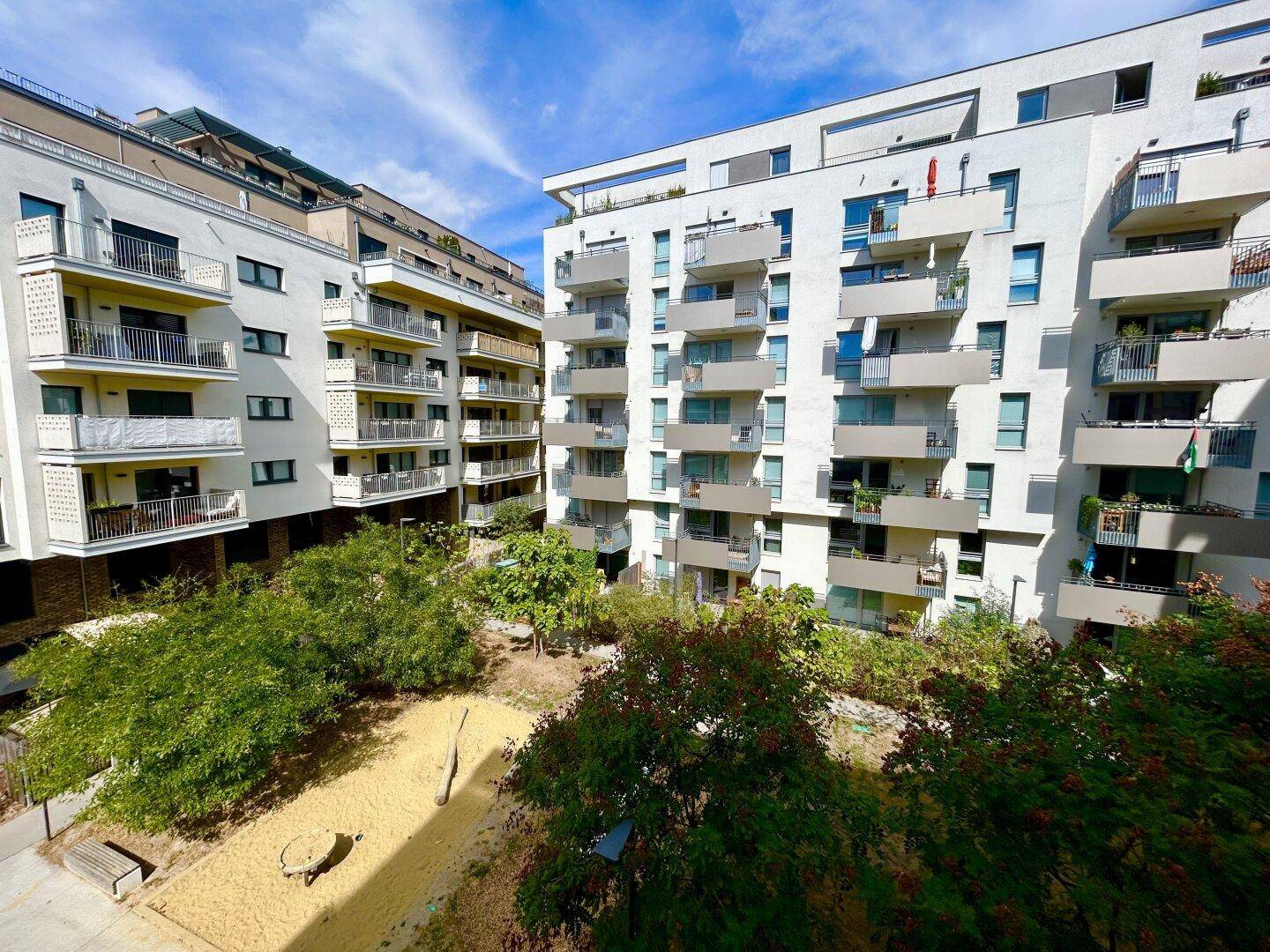 Moderne Wohnanlage mit begrüntem Innenhof und Spielplatz, umgeben von weiteren Gebäuden.