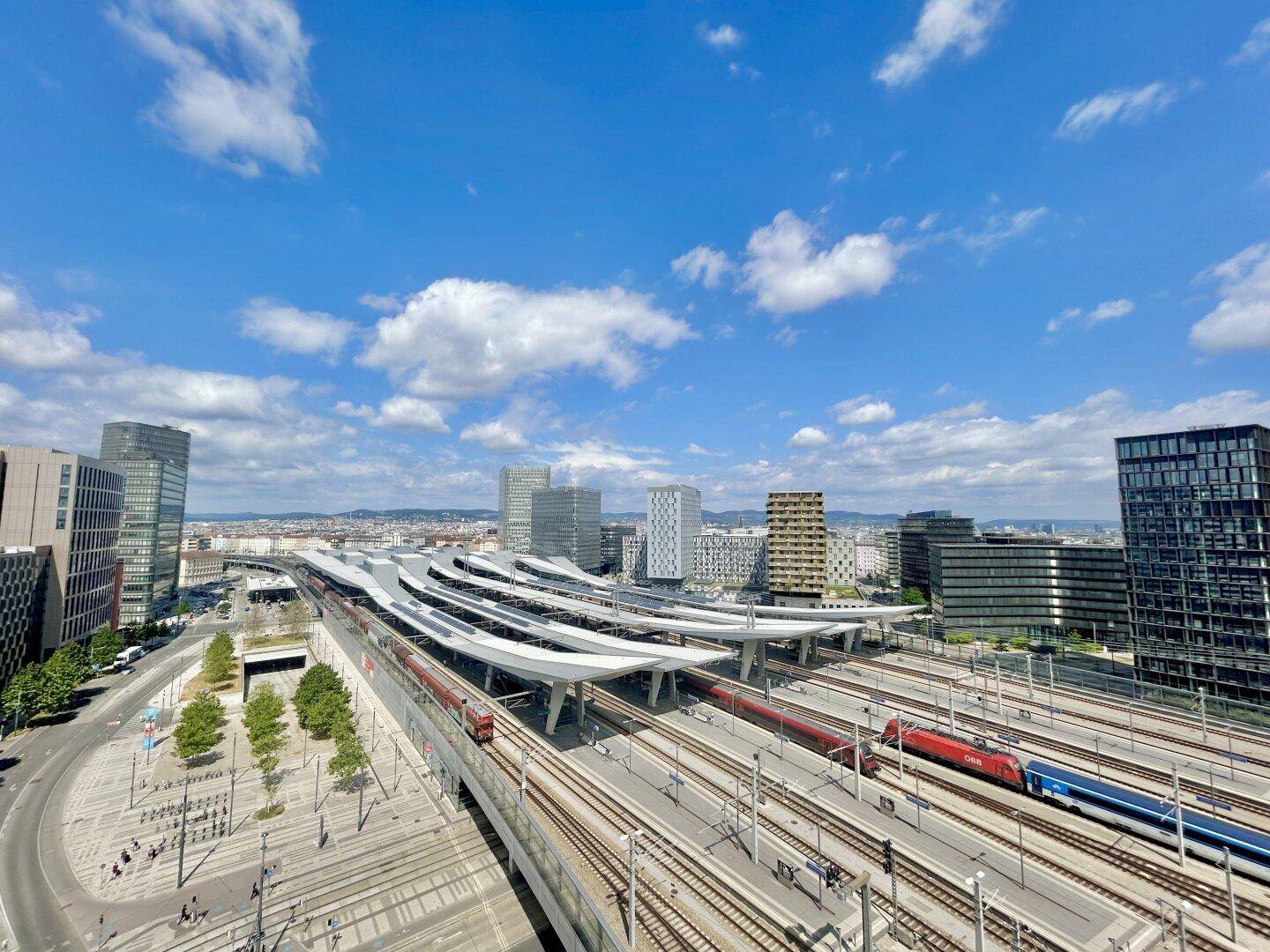 Panoramablick auf den Hauptbahnhof und die moderne Stadtlandschaft unter blauem Himmel.