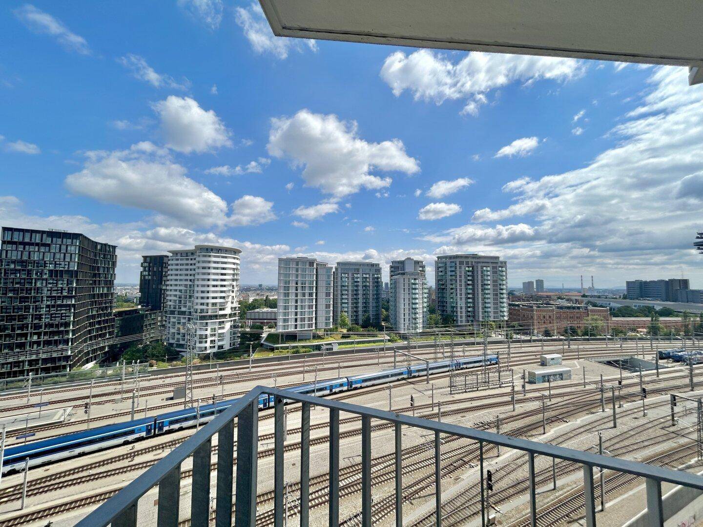 Weitläufiger Blick über die Bahngleise und die moderne Skyline der Stadt.