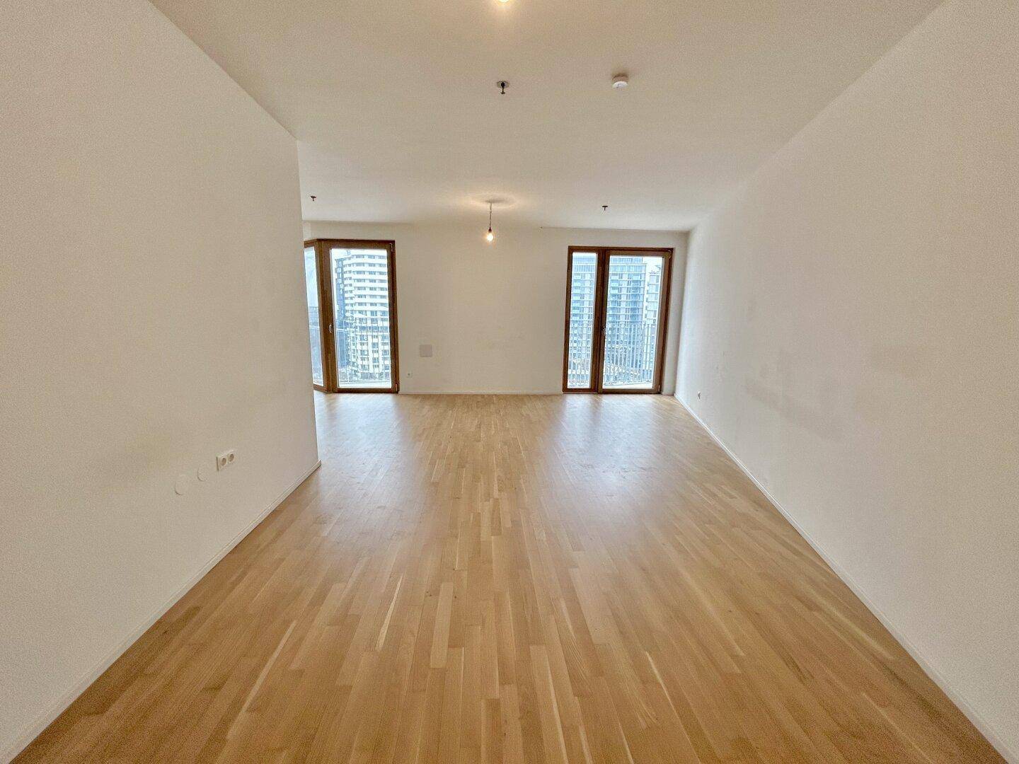 Heller Wohnraum mit Parkettboden und hohen Fenstern, die einen weiten Blick bieten.