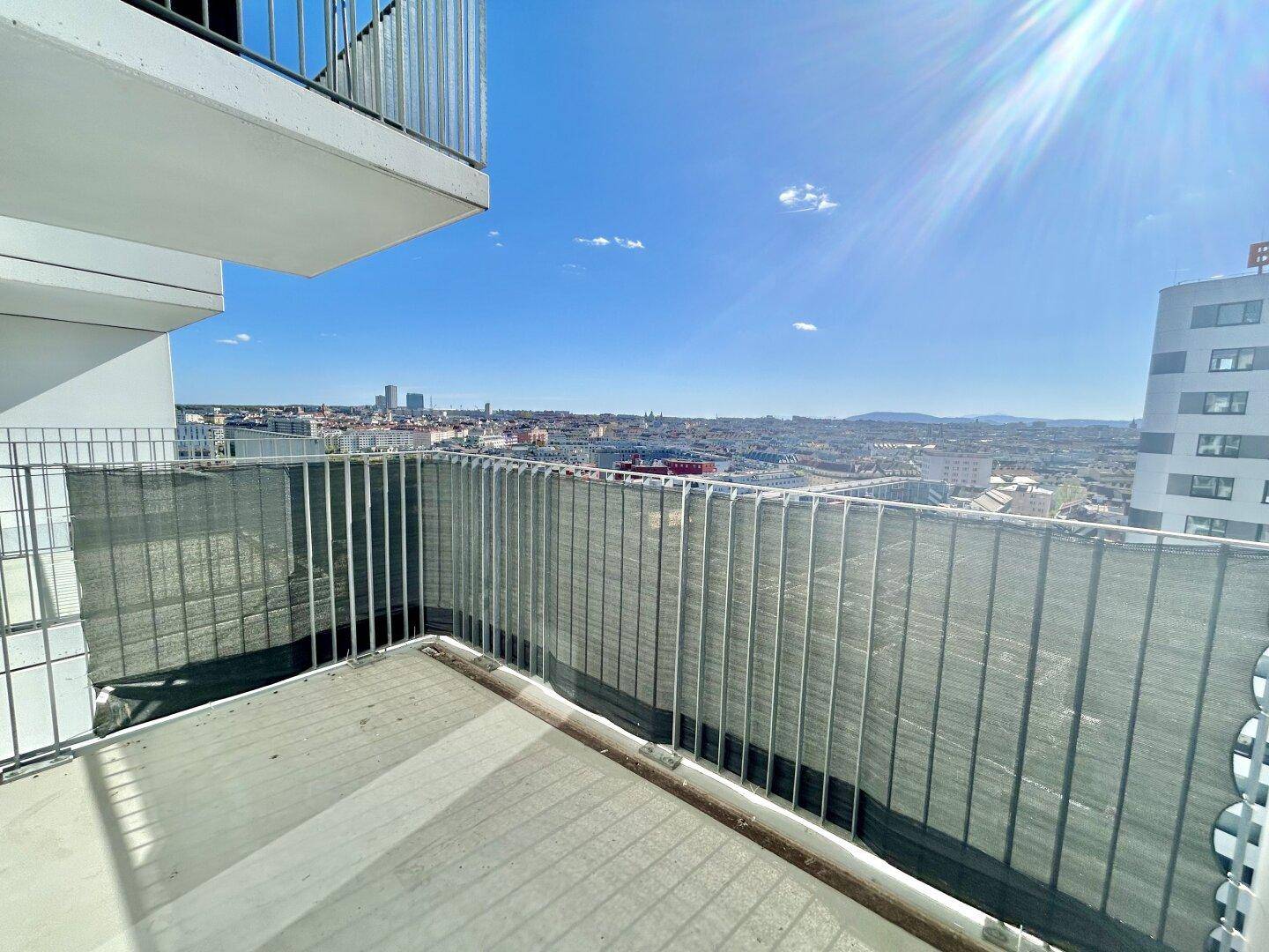 Sonniger Balkon mit weitem Blick über die Stadt und die umliegende Bebauung.