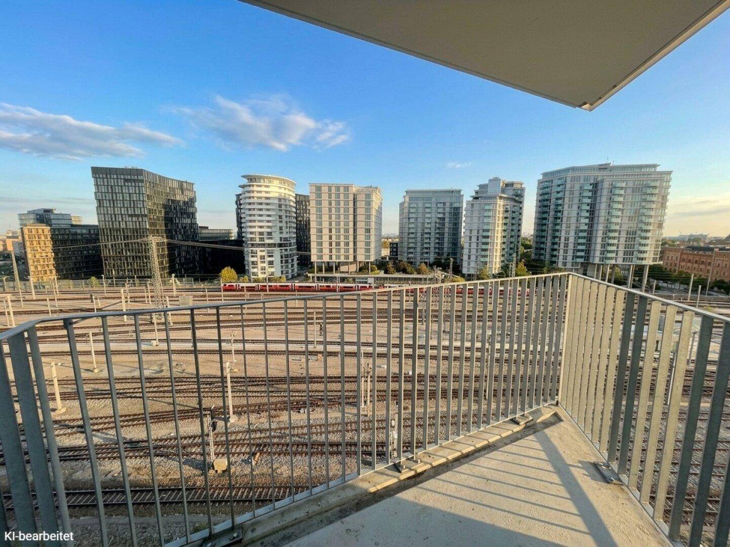 Balkon mit Blick auf die Stadt und Bahngleise, umgeben von modernen Gebäuden.