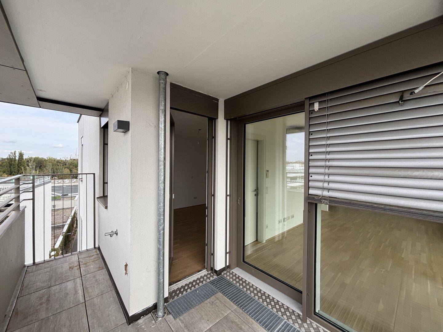 Kleiner Balkon mit Fliesenboden und Blick auf die Umgebung, ausgestattet mit Rollladen.