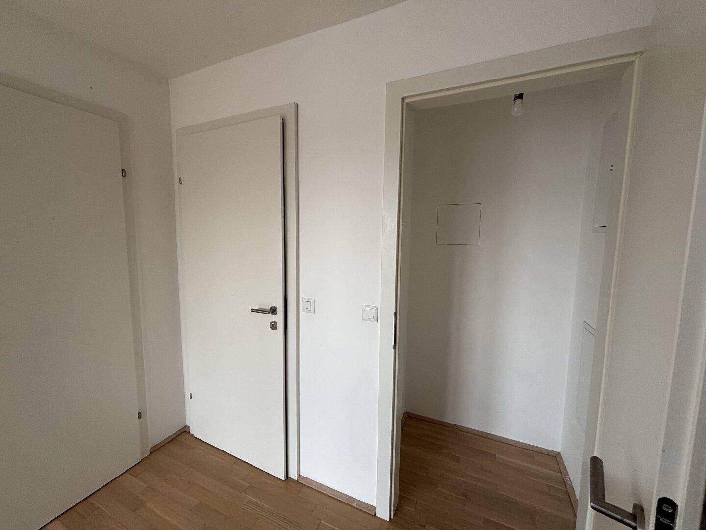 Kleiner Abstellraum oder Nische mit Parkettboden neben einer Tür.