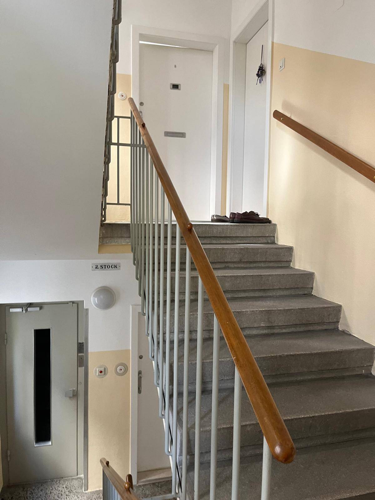 Treppenhaus in einem Mehrfamilienhaus mit Holzgeländer und Betontreppen.