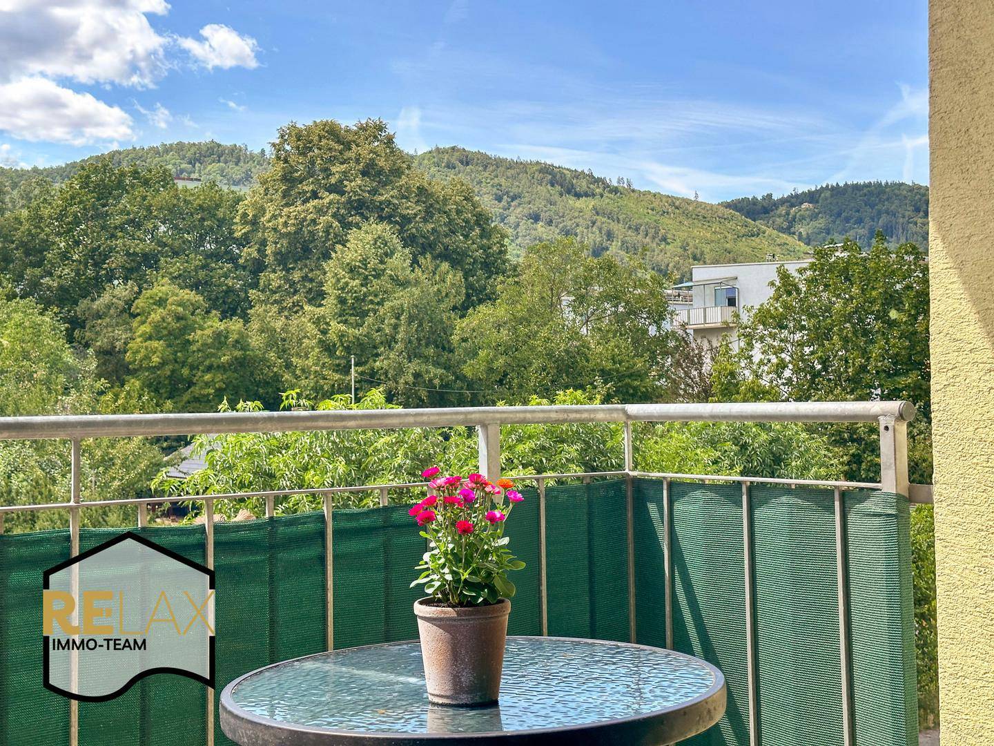 Gemütlicher Balkon mit kleinem Tisch und Pflanzen, bietet einen schönen Blick ins Grüne.