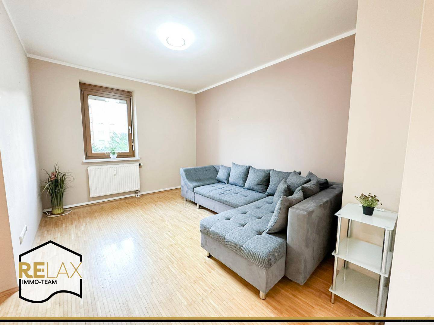 Gemütliches Wohnzimmer mit großem Ecksofa, Holzparkett und viel Tageslicht.