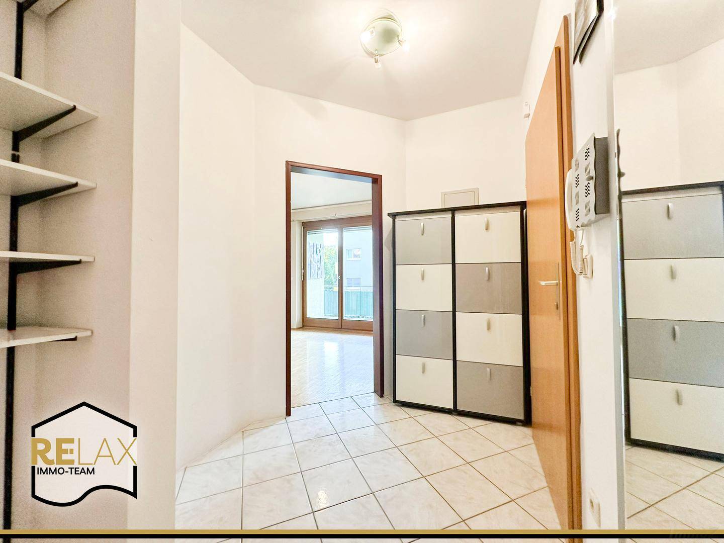 Heller Flur mit Fliesenboden, praktischem Schuhschrank und offenen Regalen.