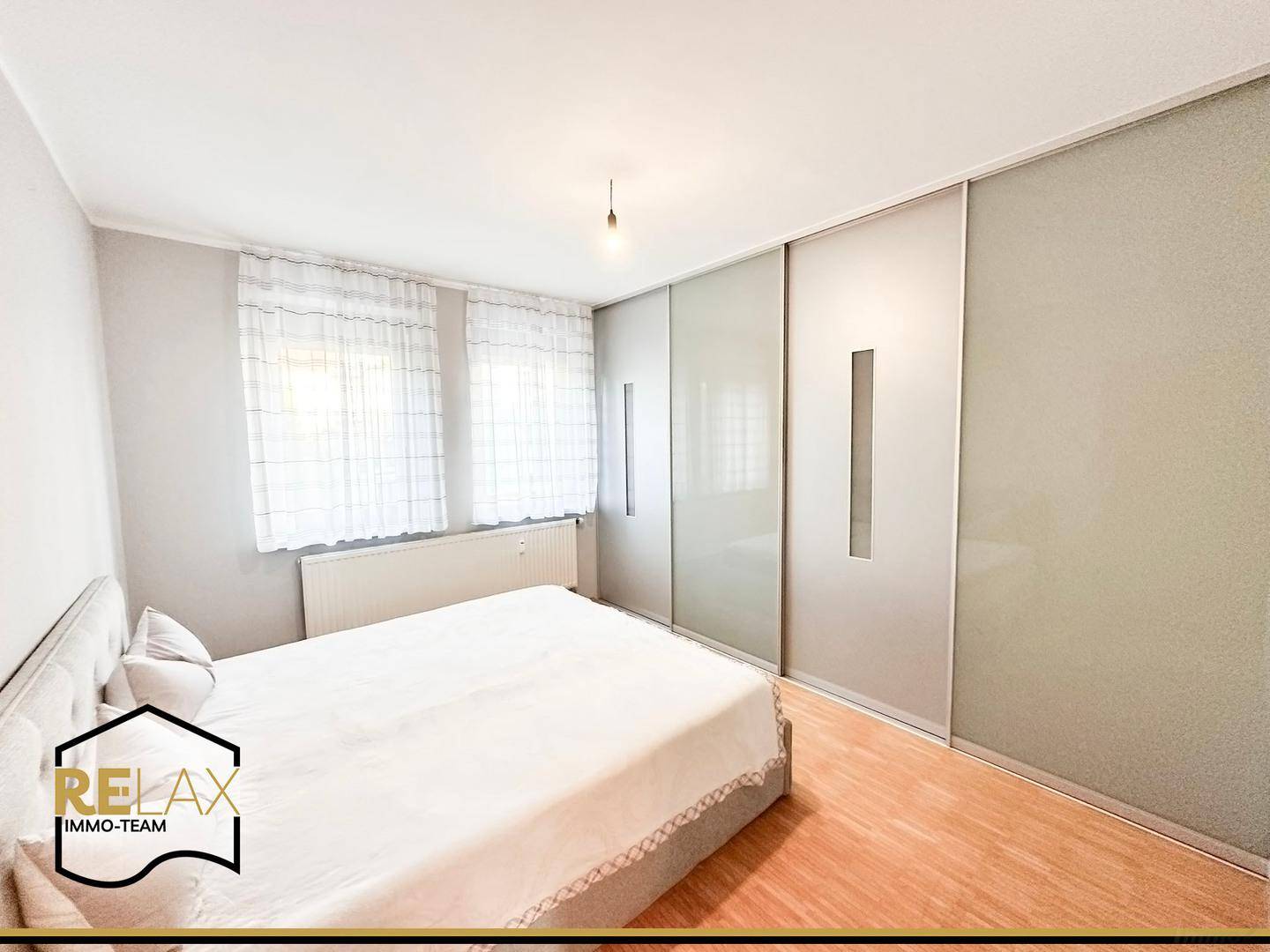Gemütliches Schlafzimmer mit Doppelbett, Holzparkett und einem großen Einbauschrank.