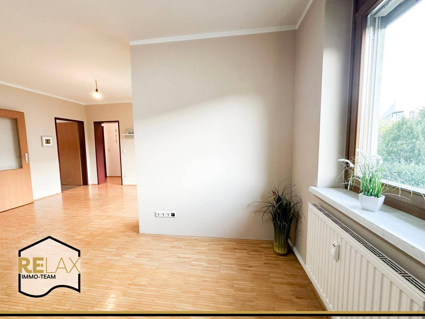 Heller Raum mit Holzparkett, großem Fenster und Heizkörper, bereit zur individuellen Gestaltung.