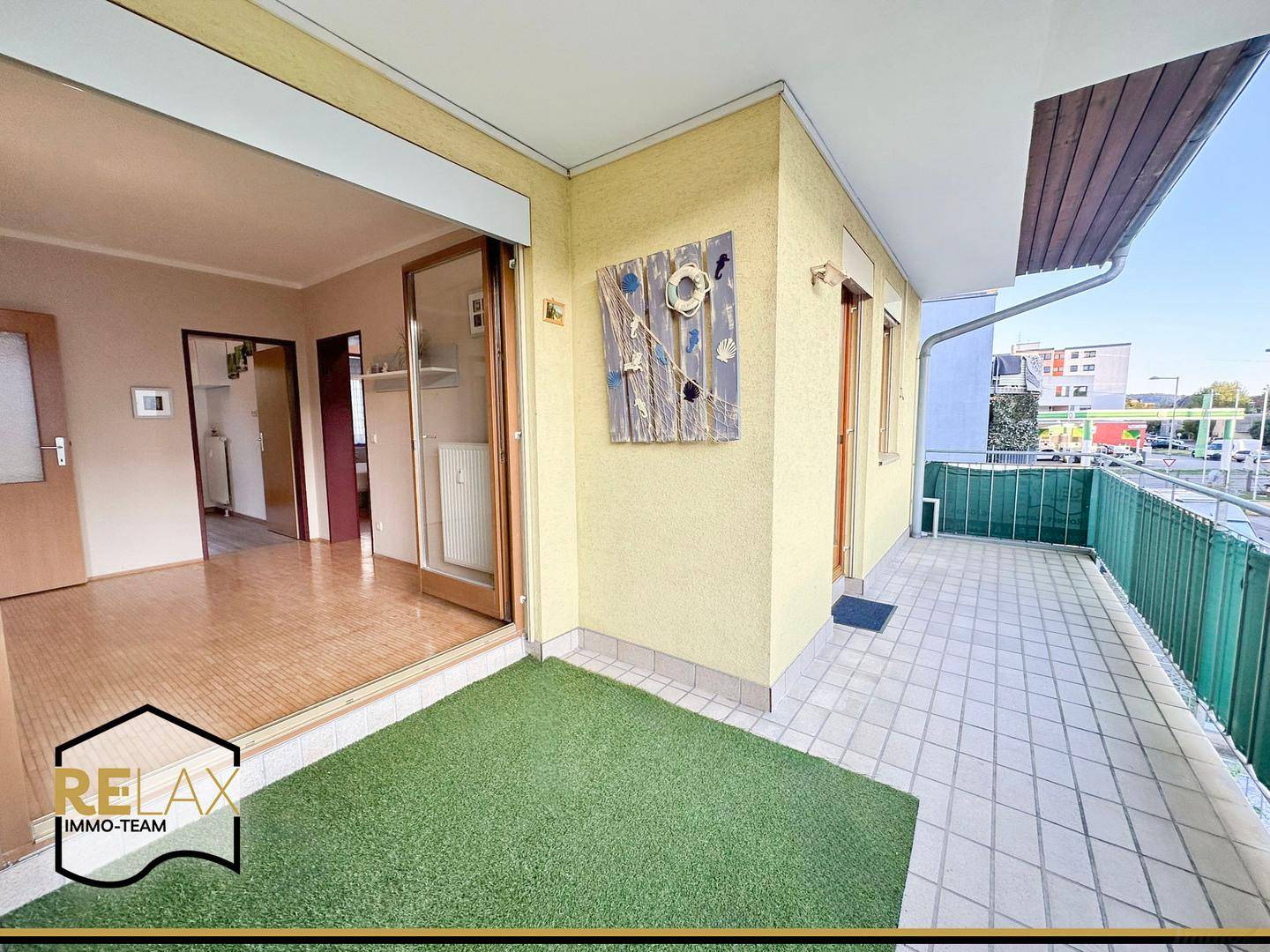 Geräumiger Balkon mit Kunstrasen und Fliesenboden, mit Blick auf die Umgebung.