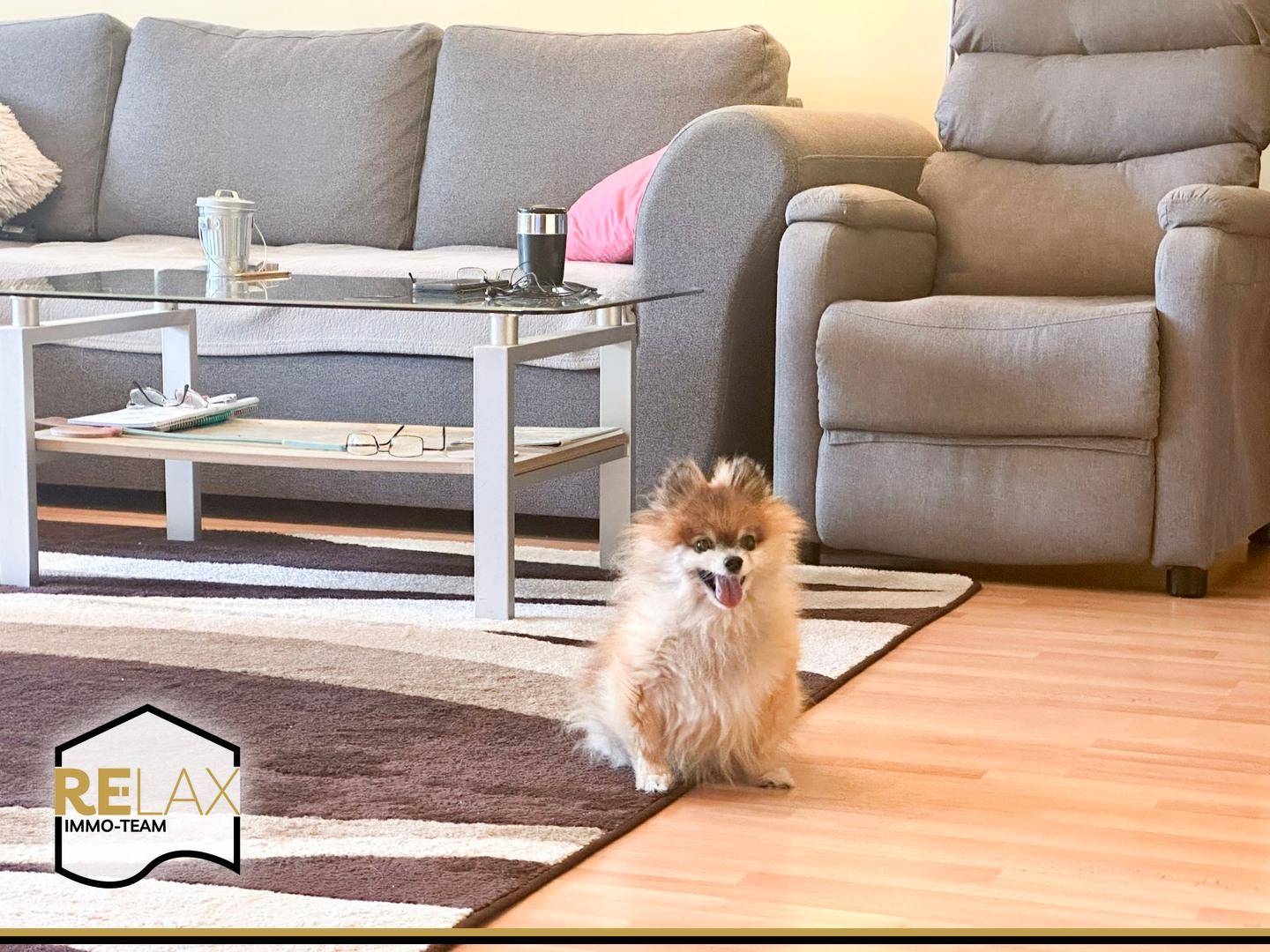 Gemütlicher Wohnbereich mit grauem Sofa, Teppich und einem kleinen Beistelltisch.