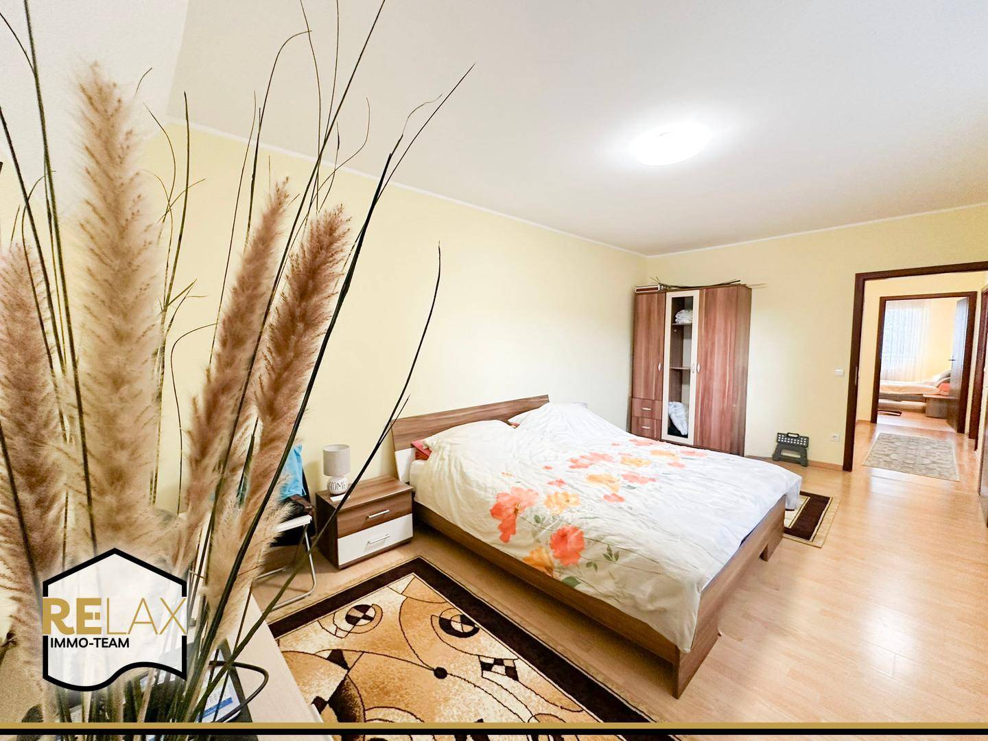 Schlafzimmer mit Doppelbett, Holzmöbeln und hellem Parkettboden.