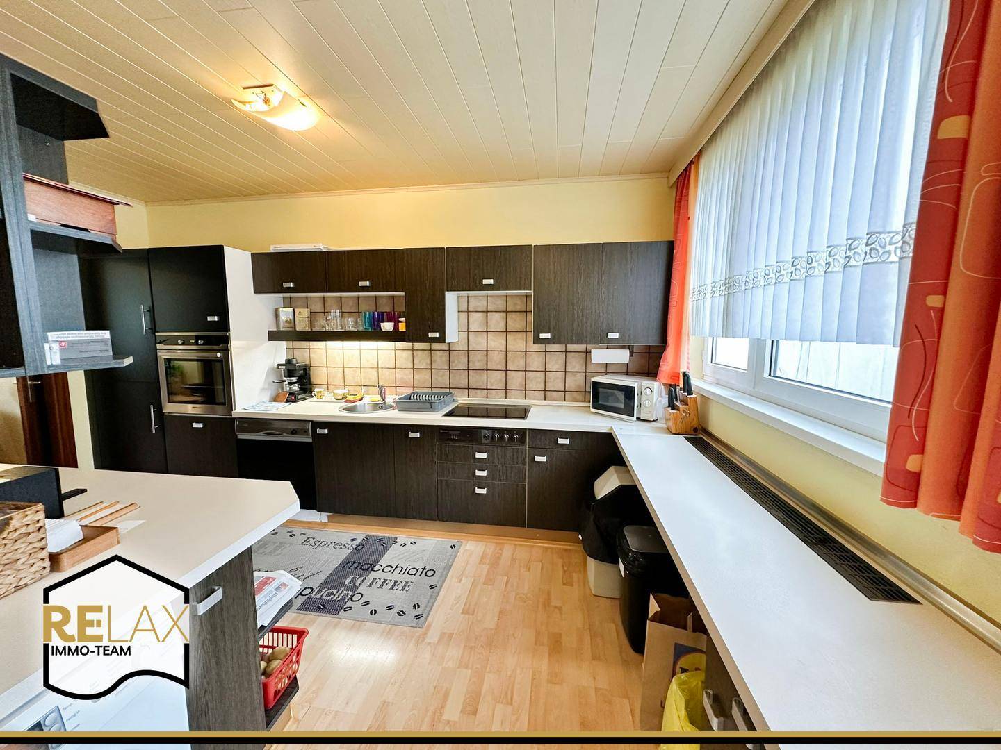 Funktionale Küche mit dunklen Holzschränken, integrierten Geräten und Fenster.