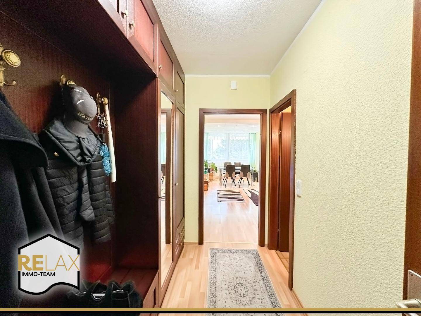 Eingangsbereich mit Garderobe, Spiegel und Parkettboden, der zu den Wohnräumen führt.