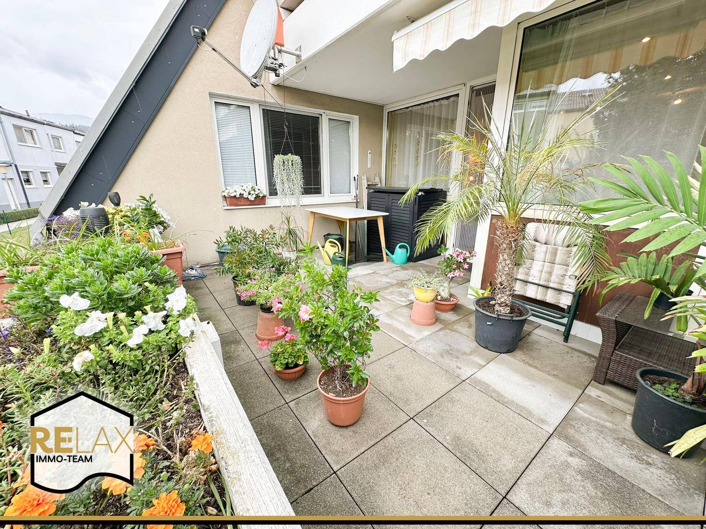 Weitläufige Terrasse mit Markise, vielen Pflanzen und Sitzgelegenheiten im Freien.
