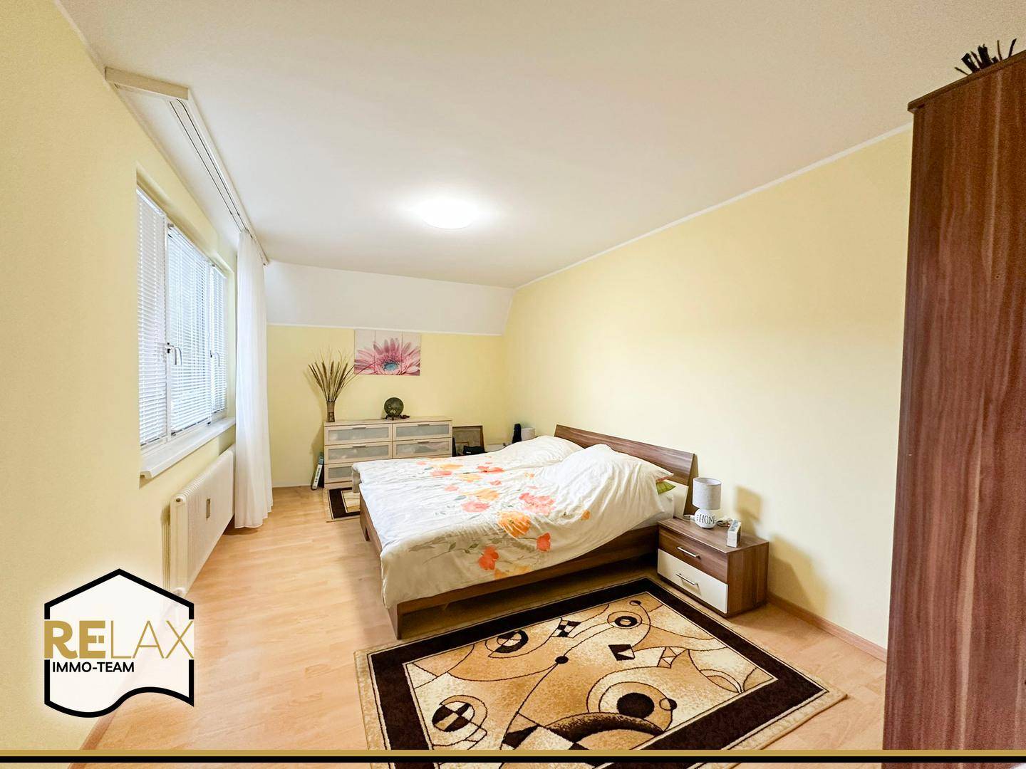Schlafzimmer mit Doppelbett, Nachttischen und einem großen Fenster für natürliche Belichtung.