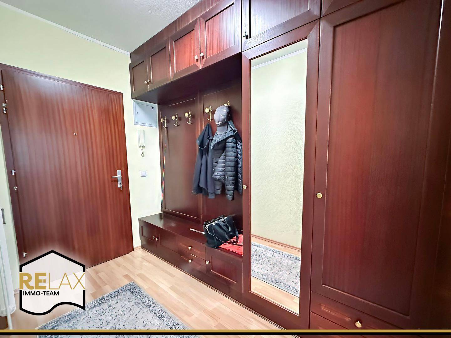 Eingangsbereich mit großer Garderobe, Spiegel und Holzboden, der zur Wohnung führt.