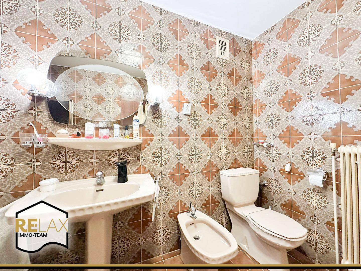 Badezimmer mit Badewanne, Bidet, Toilette und auffälligen Fliesen im Retro-Stil.