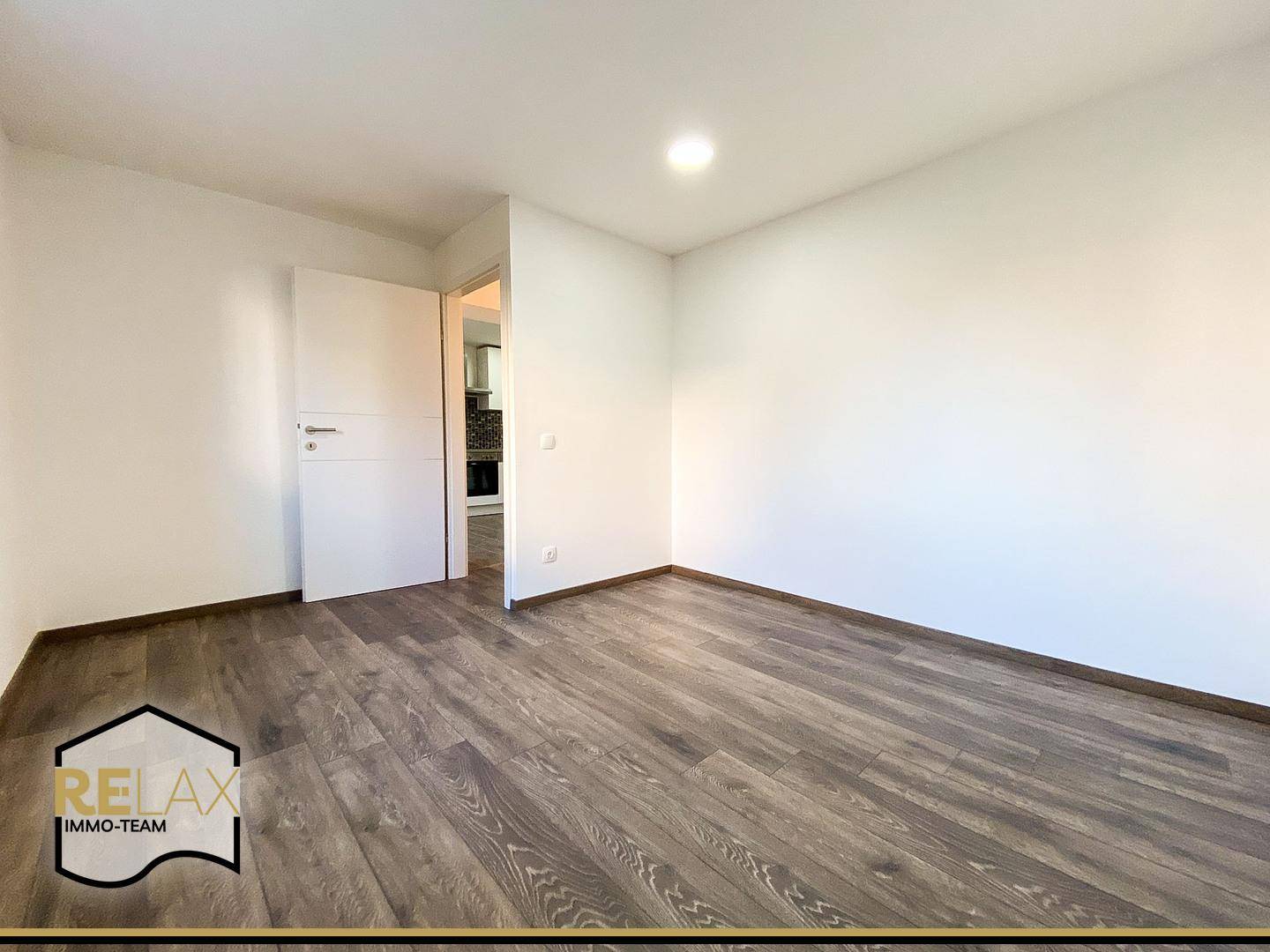 Helles Schlafzimmer mit Laminatboden und weißer Tür, bietet eine ruhige und einladende Atmosphäre.