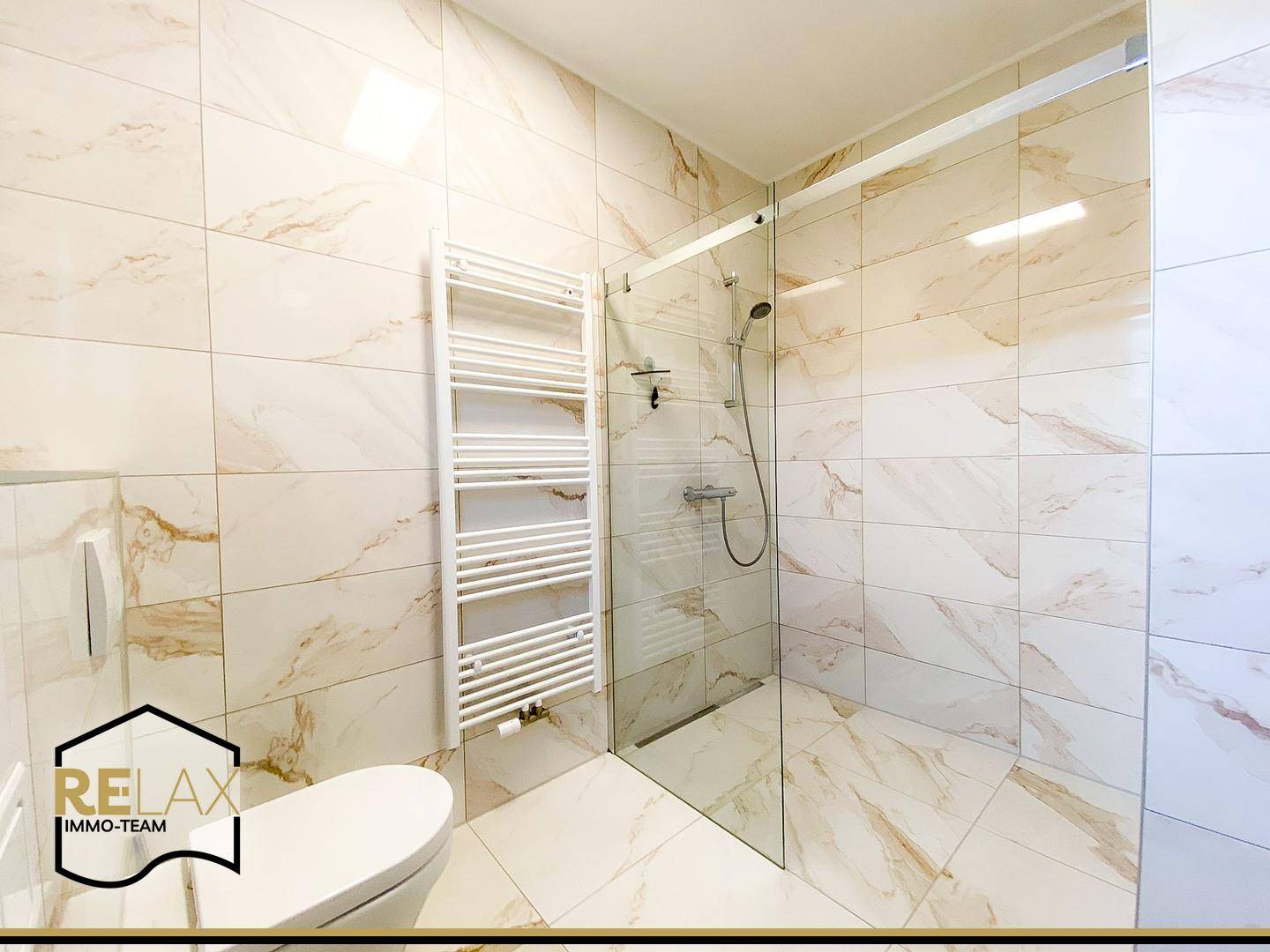 Modernes Badezimmer mit beigefarbenen Marmorfliesen, bodengleicher Dusche und Wand-WC.