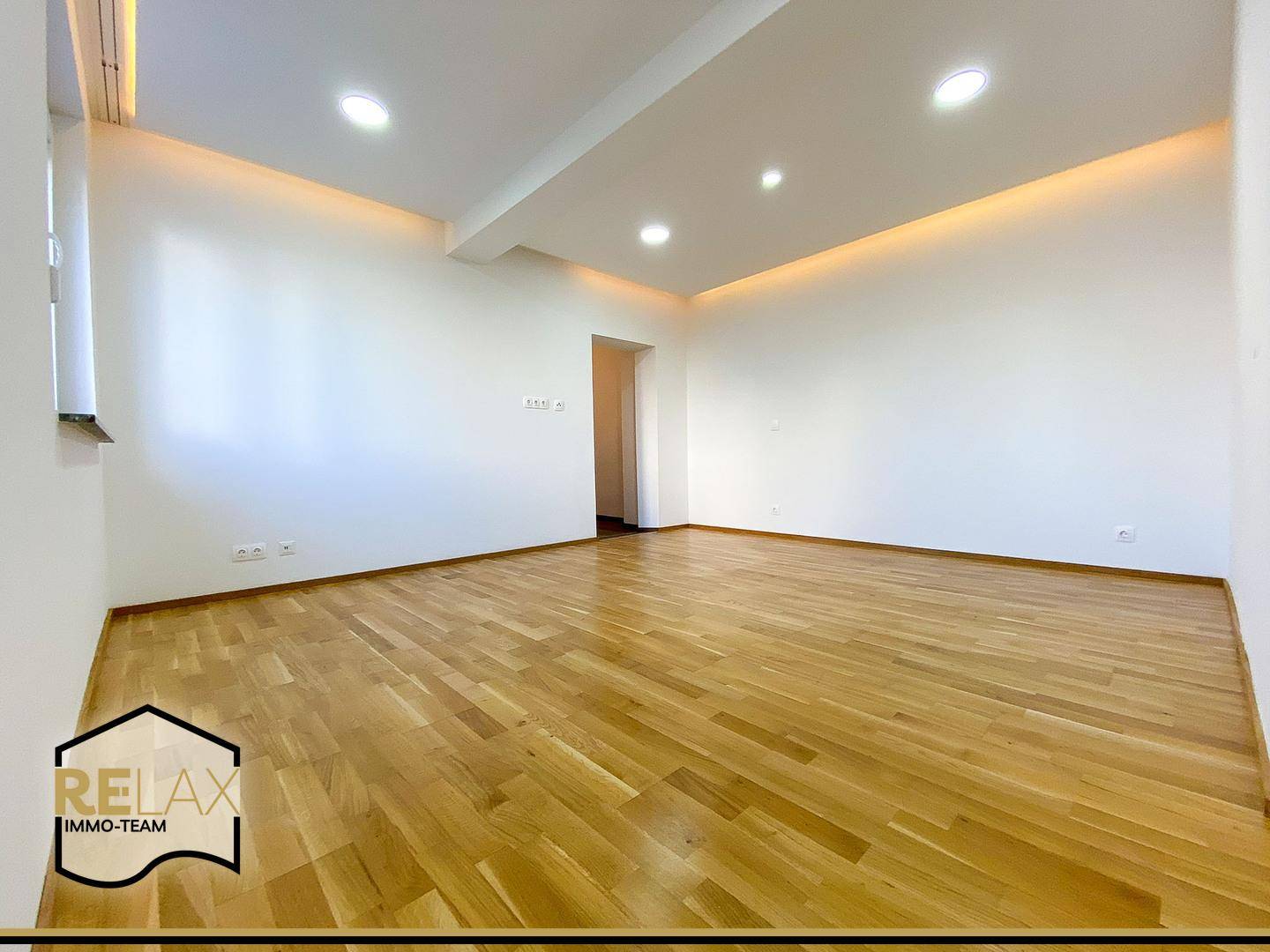 Lichtdurchfluteter Raum mit Holzparkett und moderner Beleuchtung, bietet viel Platz für individuelle Gestaltung.