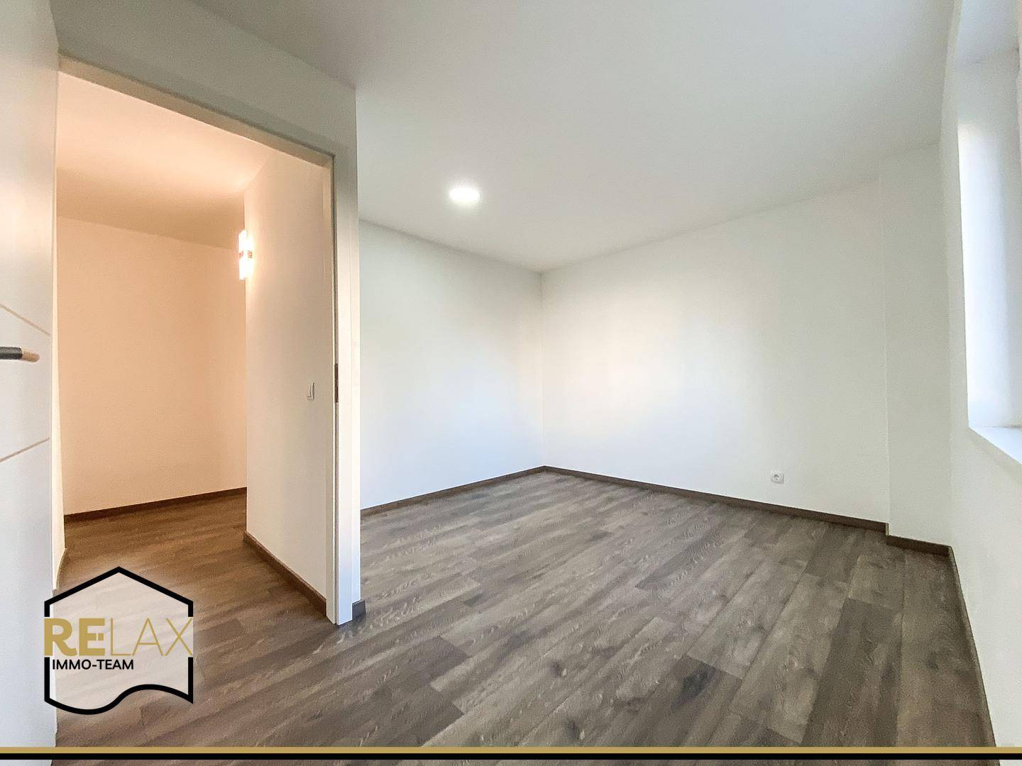 Geräumiges Zimmer mit modernem Laminatboden und weiß gestrichenen Wänden, bereit zur Einrichtung.