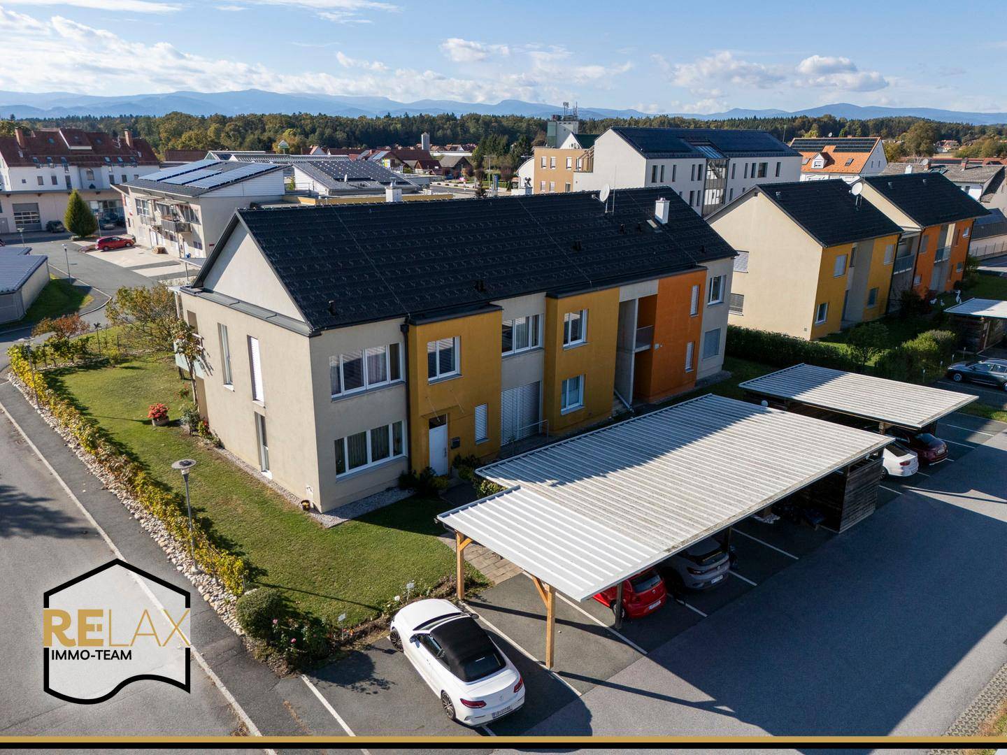 Luftaufnahme der Wohnanlage mit Carports und umliegender Bebauung an einem sonnigen Tag.